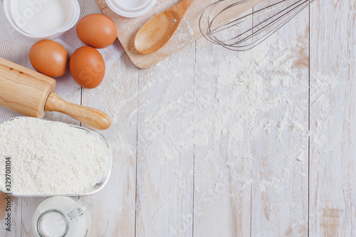 Homemade Dough Recipe (Eggs, flour, milk, sugar) and wooden kneading dough on a wooden table, view from above