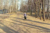 child 4 years old rides a yellow scooter on a dirt road in a city park