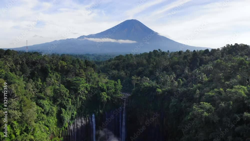 AERIAL: flying backwards shot of a beautiful waterfall in Indonesia called 