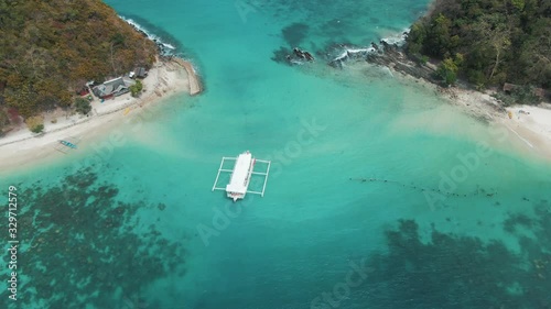 Beautiful blue sea water with a white boat anchored between two remote islands in south east asia photo