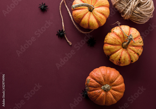 Dark red, purple Halloween background with orange pumpkin and black spiders, copy space