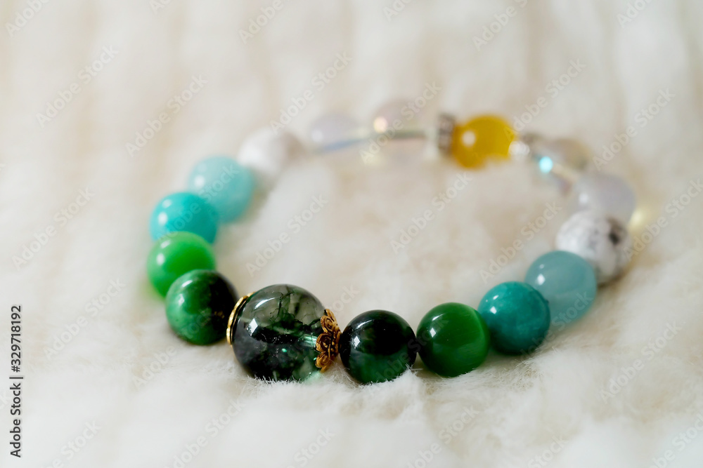 Green and white tone lucky stone bracelet. green moss agate, Green tiger's eye, jade on white wool background. supplement Fortify Fortunate charm and rich Green and white tone lucky stone bracelet. green moss agate, Green tiger's eye, jade on white wool background. supplement Fortify Fortunate charm and rich
