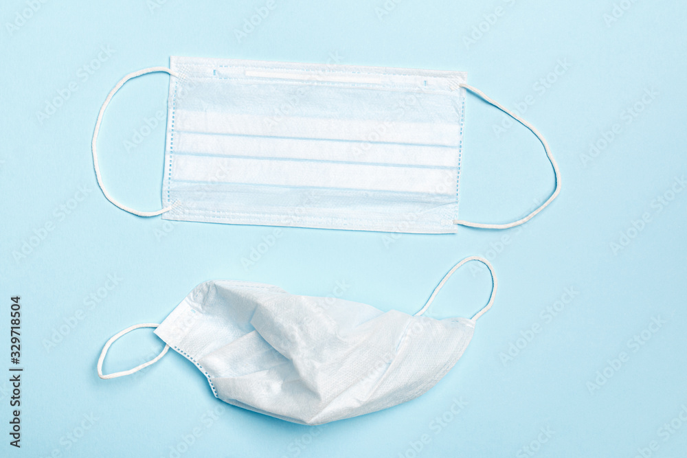New and used protective disposable medical masks on a blue background