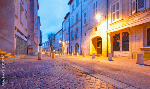 Narrow street with typical orange houses at dusk - Avignon city, France 