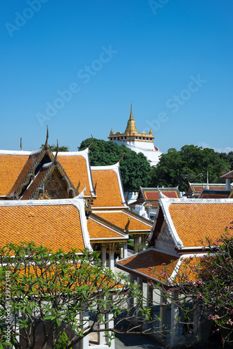 The scenery of Wat Phu Khao Thong (Golden Mount) or Wat Saket temple among the roof of temple in Bangkok, Thailand. photo