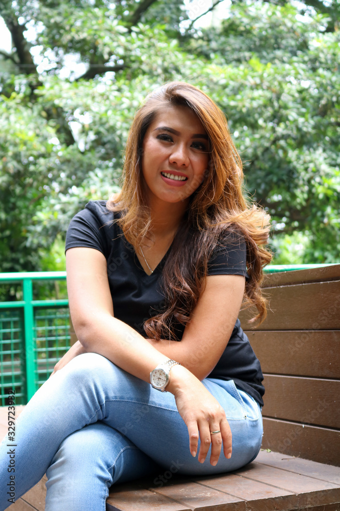 Young female wearing black t shirt and posing in the park. Suitable for mock up design template. Young female wearing black t shirt and posing in the park. Suitable for mock up design template.