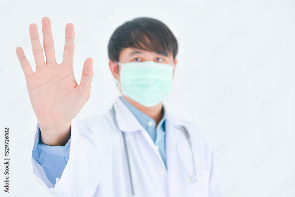Asian male doctor wearing medical mask shows warning stop sign by his hand over white background. Asian male doctor wearing medical mask shows warning stop sign by his hand over white background.
