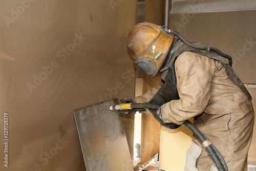 Bilde på lerret Man in protective clothing cleans industrially with high-pressure sandblasting