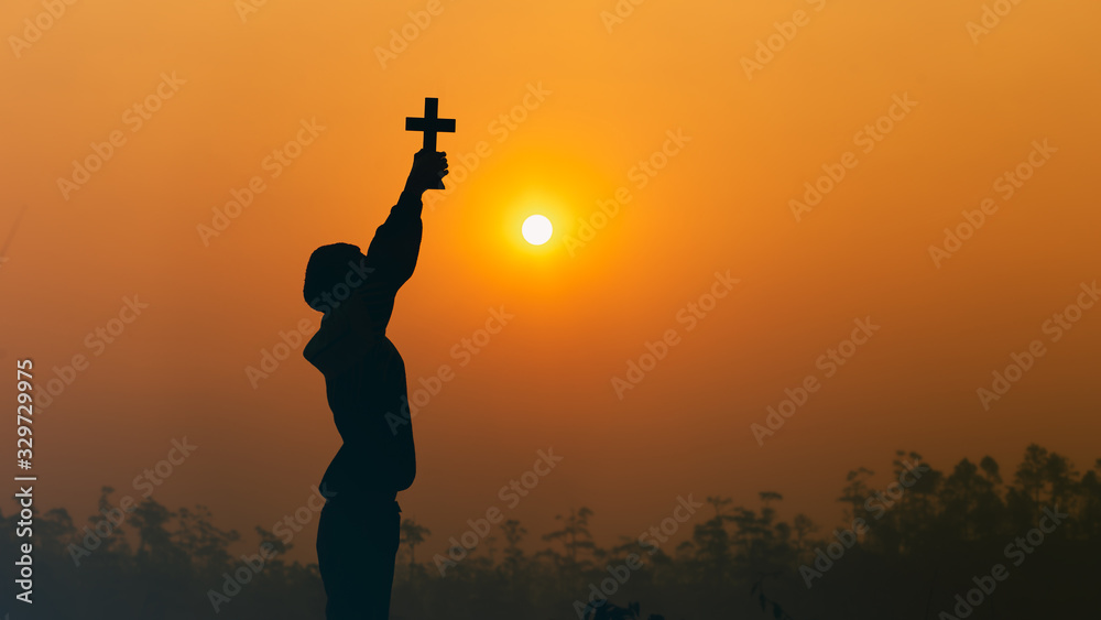 Human lift the Cross up to sky with praying and worship God in morning light, christian silhouette concept.