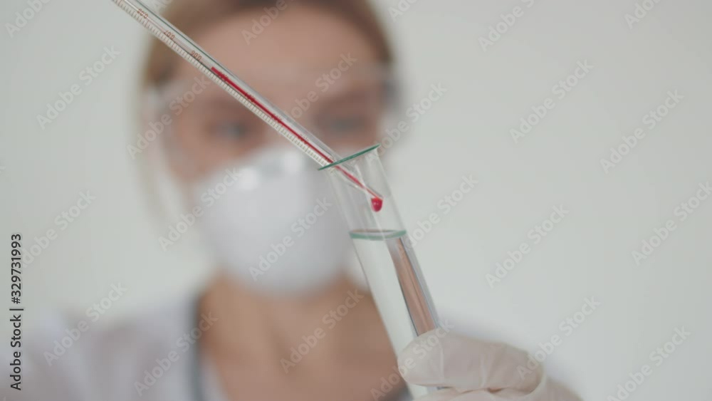 A young lab worker makes a blood test of a person with a coronavirus Covid-19. A test tube with a solution in which the medic drops a drop of blood A young lab worker makes a blood test of a person with a coronavirus Covid-19. A test tube with a solution in which the medic drops a drop of blood