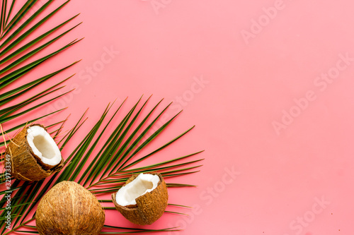 Exotic background with coconuts and palm leaves on pink background top-down frame copy space