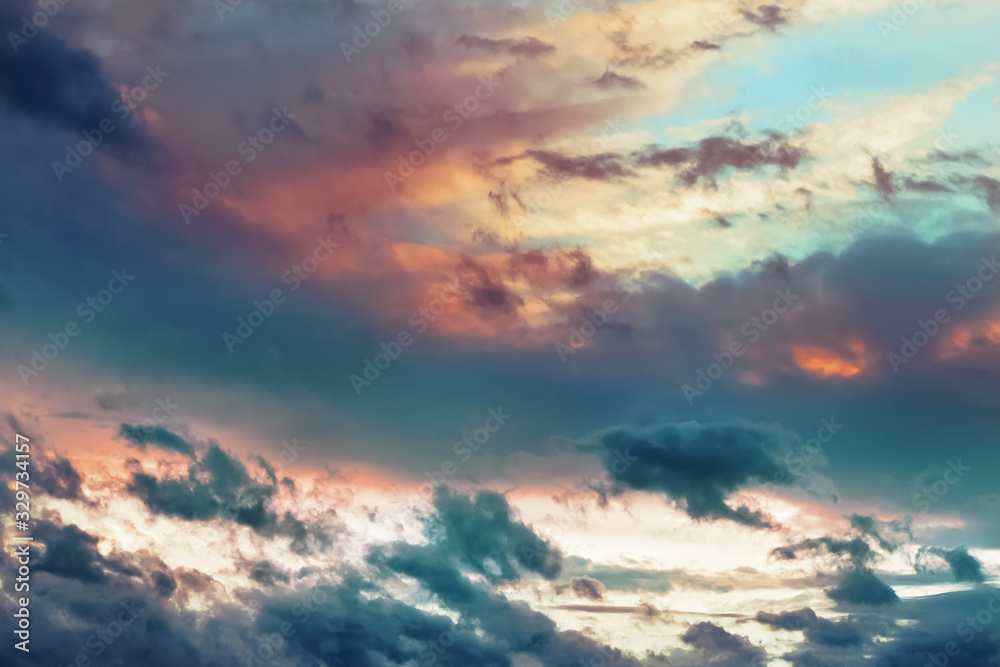 Obraz premium Beautiful dramatic clouds in the sky painted in vibrant juicy colors at sunset. Abstract bright cloudy background