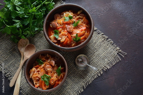 Cabbage stew with grilled sausage in tomato sauce - traditional dish of German, Polish or Russian cuisine