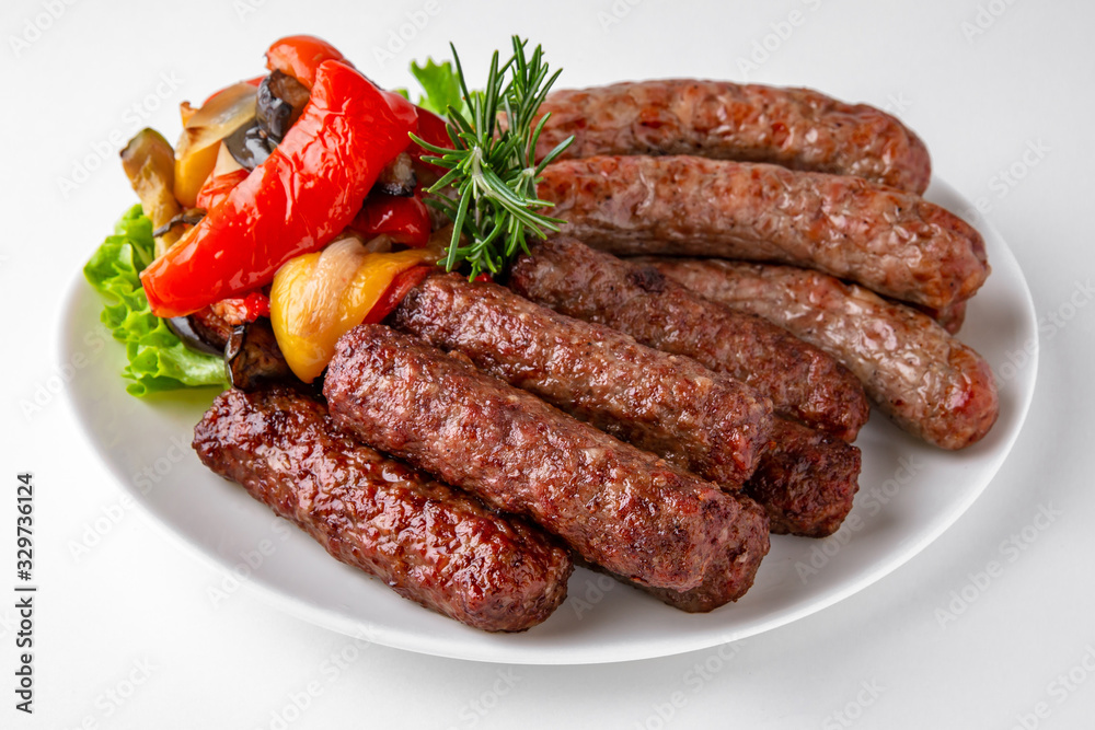 Grilled pork and beef sausages with vegetables. Banquet festive dishes. Gourmet restaurant menu. White background.