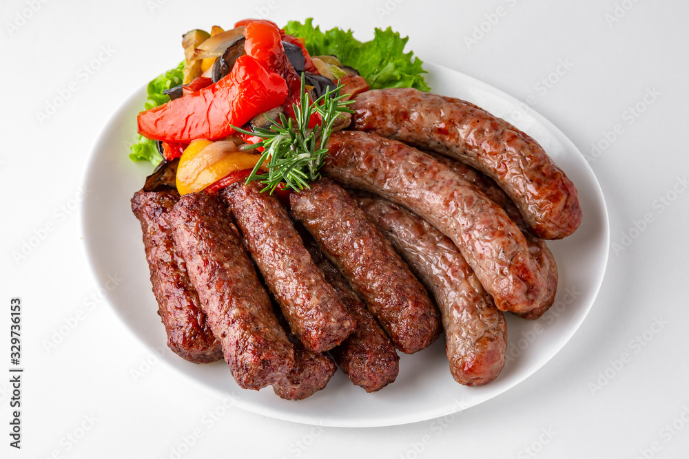 Grilled pork and beef sausages with vegetables. Banquet festive dishes. Gourmet restaurant menu. White background. Grilled pork and beef sausages with vegetables. Banquet festive dishes. Gourmet restaurant menu. White background.