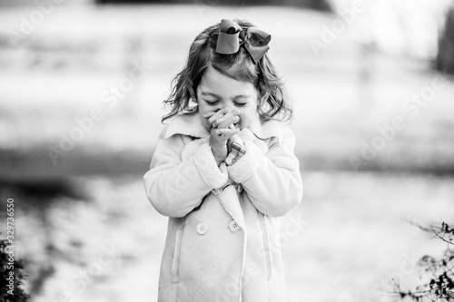 Grayscale shot of a cute girl making a wish with closed eyes photo
