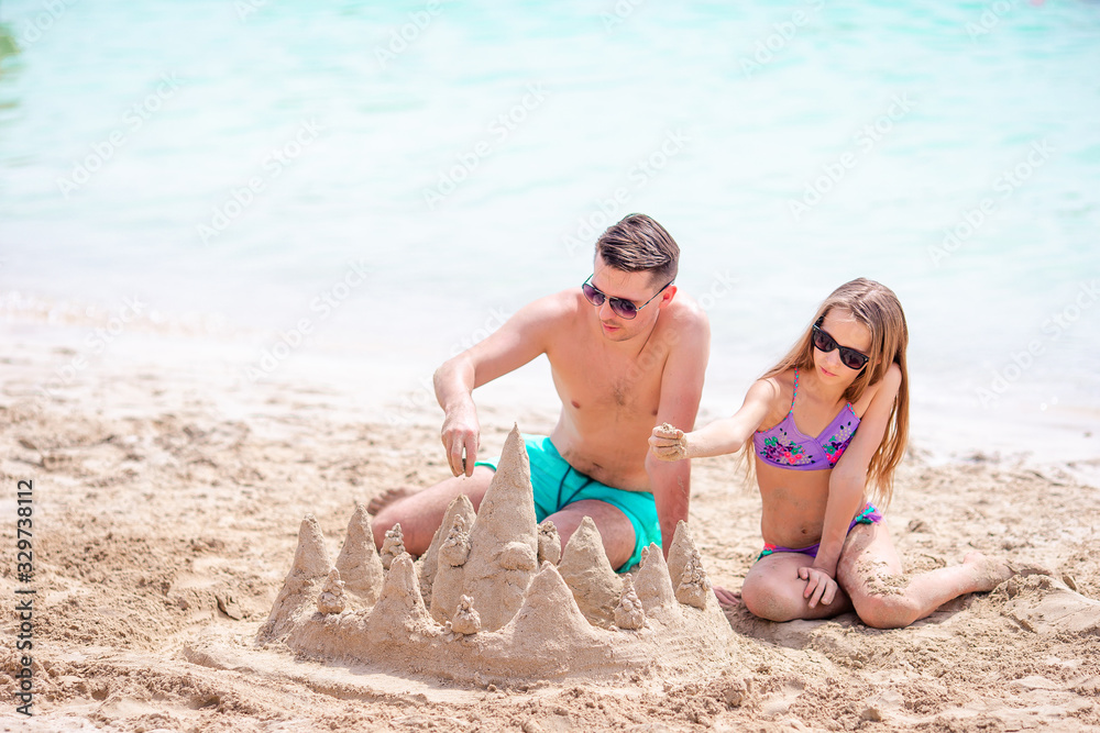 Father and kid making sand castle at tropical beach. Family playing with beach toys Father and kid making sand castle at tropical beach. Family playing with beach toys