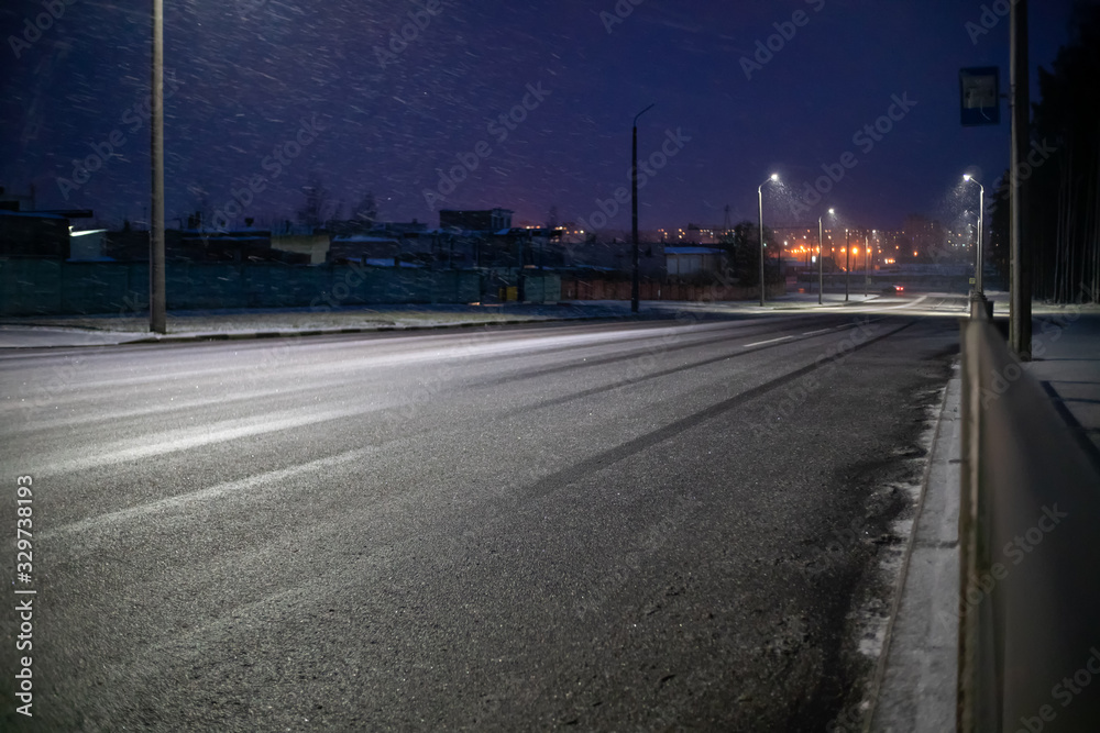 Suburban road with lights on a winter snow evening