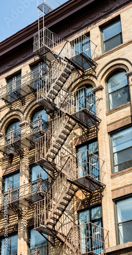 New York City Fire escape stairs. Beautiful vertical shot. Steel back staircase on a clear stone building in Soho, Manhattan. © Julien