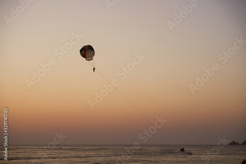 Silhouettes of people with parachute and boat. Evening, sunset. Thailand. Phuket. 