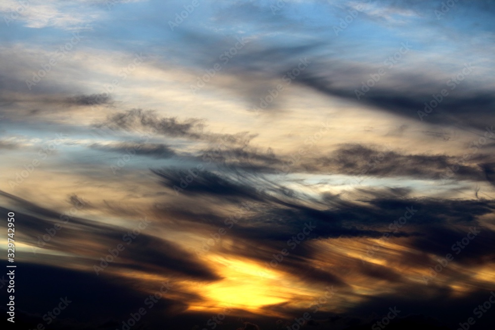 evocative sunset image with black clouds and blue sky