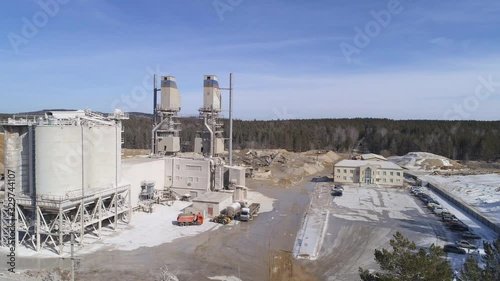 Aerial view of lime plant. Sunny spring day. In the frame are kilns, conveyors, tractors, cars and other equipment. Around the forest