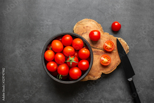 Top view of fresh red cherry tomatoes (grape tomatoes ) on dark background. Some cherry tomatoes is cutted