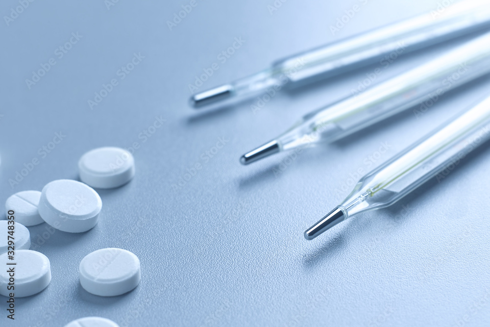 Fototapeta premium Closeup of a medical mercury thermometer and white tablets