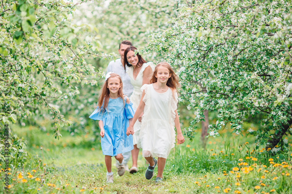 Fototapeta premium Adorable family in blooming cherry garden on beautiful spring day