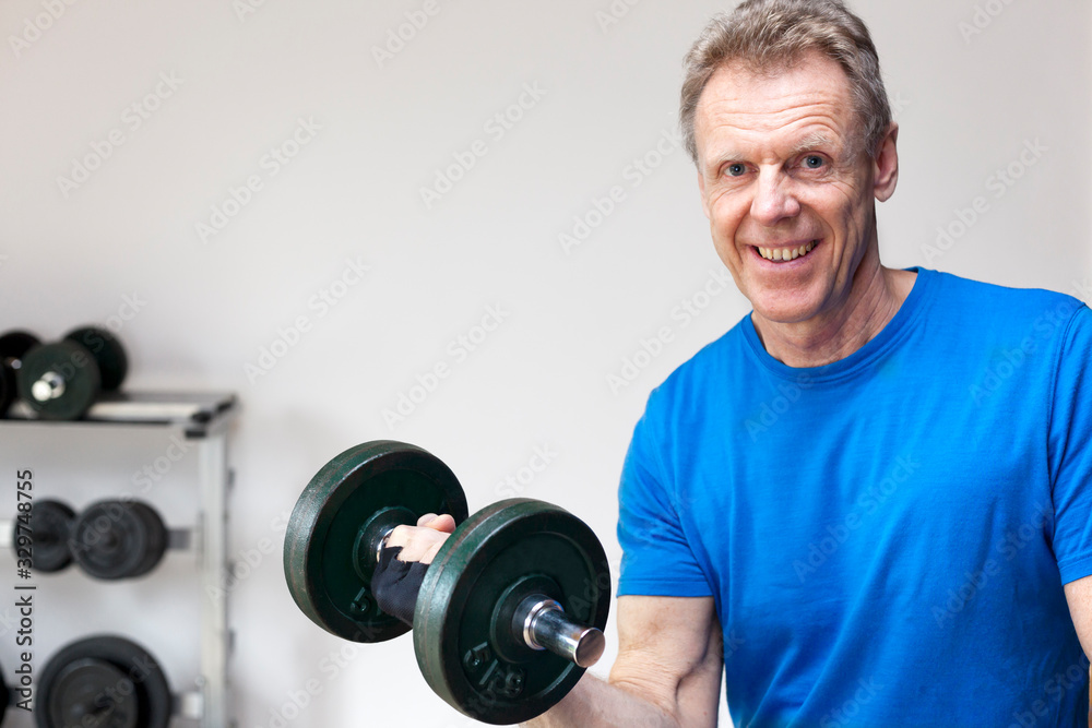 Mature smiling man working out at a gym with weights Mature smiling man working out at a gym with weights