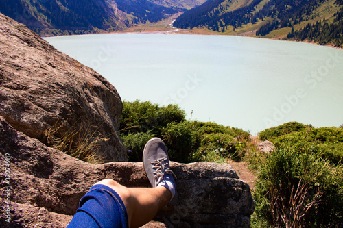 Legs resting on a mountain near calm lake water, summer day photo