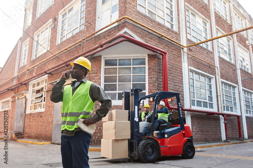 Worker with forklift and freight in front of warehouse