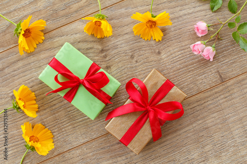 Gift boxes with flowers on the wooden background.