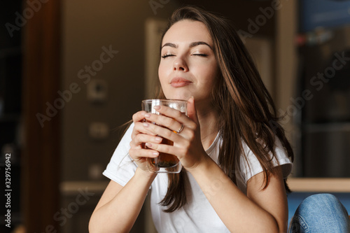Canvas-taulu Image of pleased beautiful woman drinking tea with eyes closed