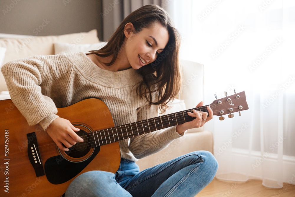 Image of happy beautiful woman playing guitar and composing song - obrazy, fototapety, plakaty 