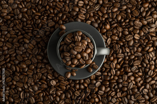 Cup with coffee beans in the center of the frame on coffee background. Flat lay
