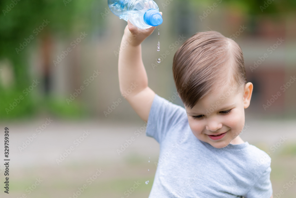 cheerful child pours water from a bottle on himself cheerful child pours water from a bottle on himself
