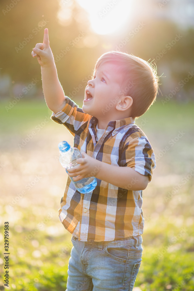 joyful child drinks clear water from a bottle on a sunny day in nature joyful child drinks clear water from a bottle on a sunny day in nature