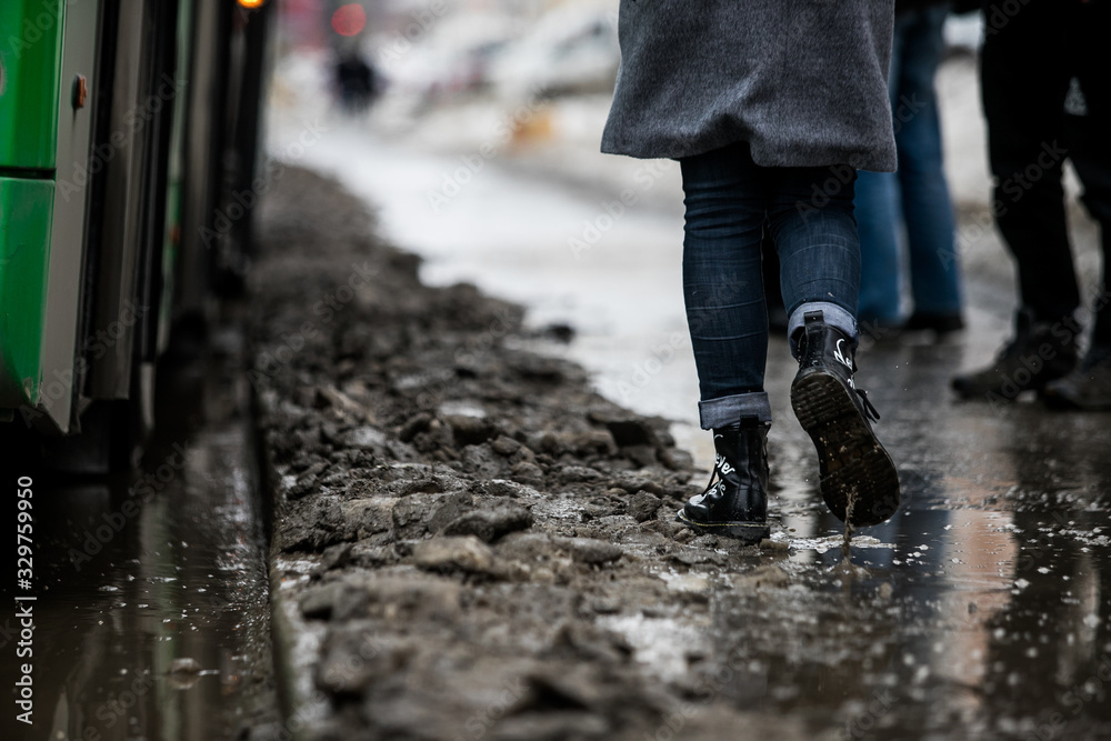 people are standing at a bus stop, getting on a bus stepping over uncleared snow and mud, special services do not clean the city people are standing at a bus stop, getting on a bus stepping over uncleared snow and mud, special services do not clean the city