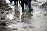 a man walks in the city on a dirty sidewalk, uncleared asphalt in the mud