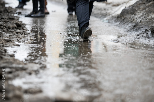 a man walks in the city on a dirty sidewalk, uncleared asphalt in the mud
