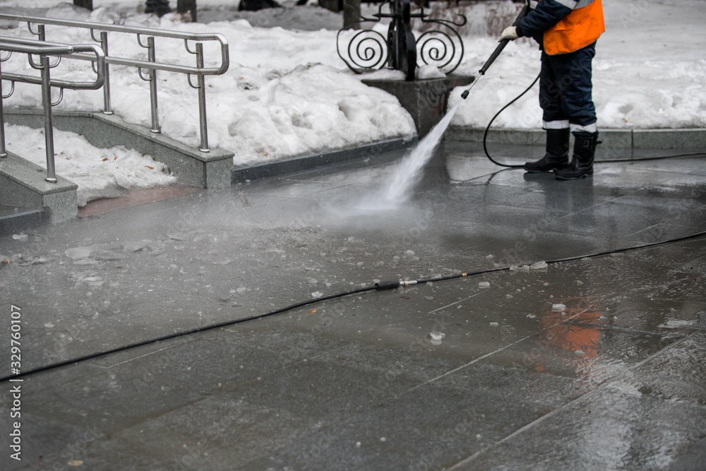Worker cleaning driveway with gasoline high pressure washer splashing the dirt, asphalt road border. High pressure cleaning Worker cleaning driveway with gasoline high pressure washer splashing the dirt, asphalt road border. High pressure cleaning