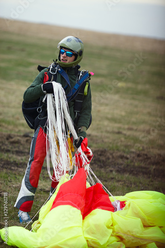 Skydiver, tandem instructor, holds in hands the slings and canopy of the parachute after landing, close-up.