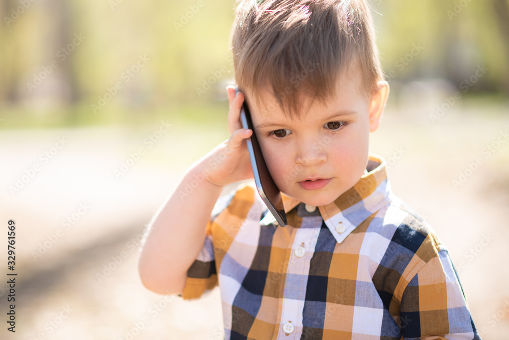 little boy speaks on the smartphone in the park little boy speaks on the smartphone in the park