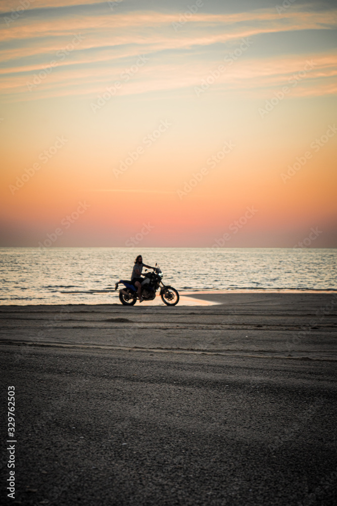 Masirah Island, Oman, January 1, 2020: Man on a motorcycle on the beach at sunset