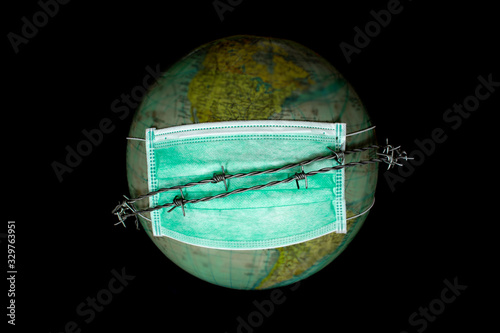 World alone in space wearing a medical mask to protect from pollution, barbed wire as symbol of not being able to leave earth, concept of protecting the world, Selected focus on mask, blurred globe