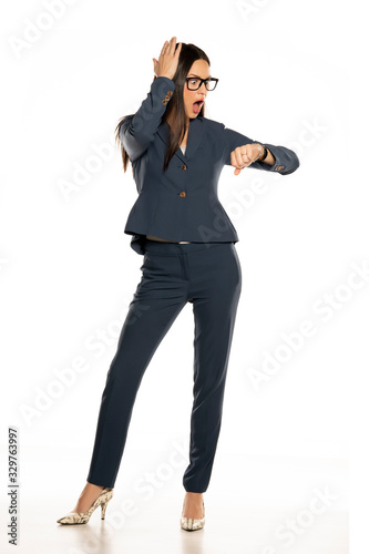 Young shocked business woman looking in her wristwatch