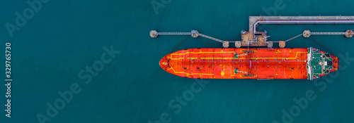 Red cargo tanker ship vessel at port with marine loading arms, Global business oversea commercial trade logistic import export oil and gas petrochemical refinery industry transport worldwide. photo