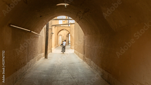 Kid on a bicycle riding in the narrow street of old city Yazd  Iran.