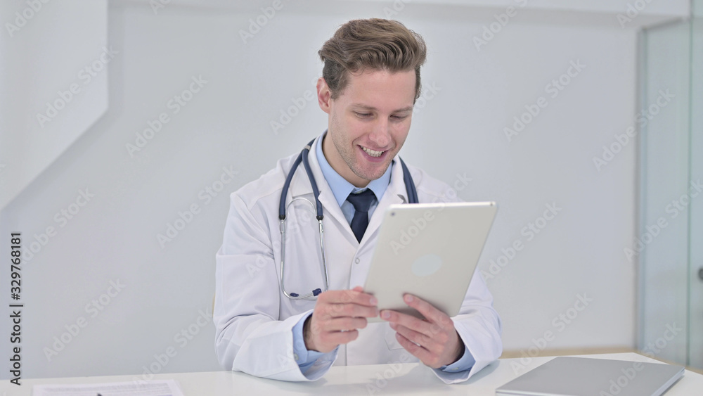 Fototapeta premium Young Male Doctor Watching Video on Tablet in Clinic